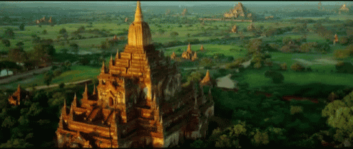 an aerial view of a temple surrounded by trees and grass