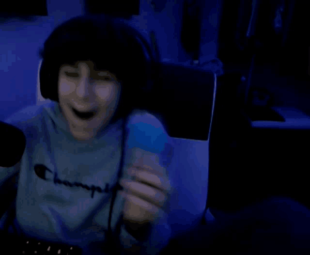 a boy wearing headphones and a champion sweatshirt is holding a blue object