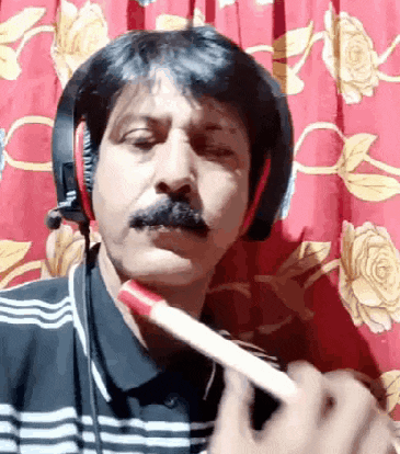a man wearing headphones is brushing his teeth with a red toothbrush .