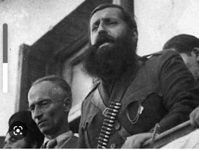 a black and white photo of a man with a beard wearing a gun belt