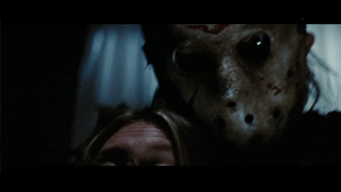 a close up of a person wearing a jason voorhees mask in a dark room