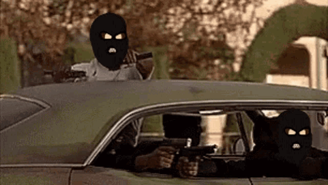 two men in ski masks are sitting in a car .
