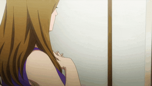 a woman in a purple top is looking at herself in a mirror