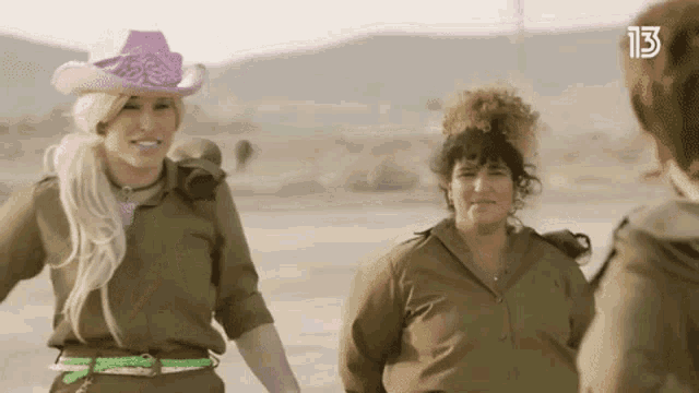 a woman in a pink cowboy hat is standing next to another woman in military uniform .