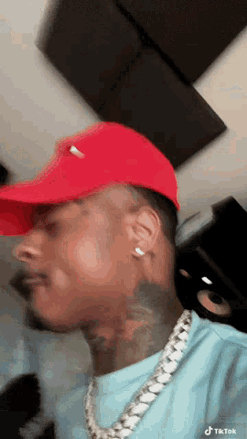 a man wearing a red hat and a chain is taking a selfie .