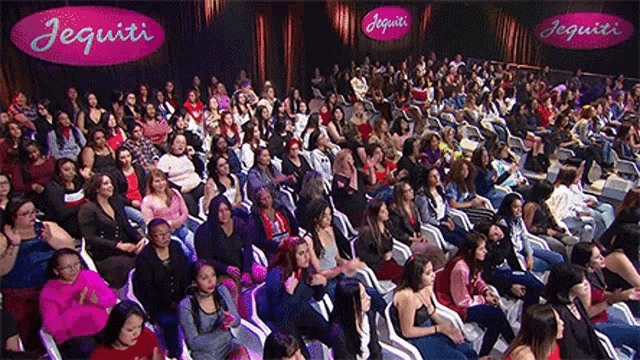 a large group of people are sitting in front of a sign for jequiti