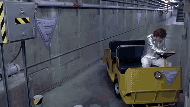 a man in a silver jacket is driving a car .