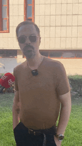 a man wearing sunglasses and a t-shirt that says ' do ' on it is standing in front of a building