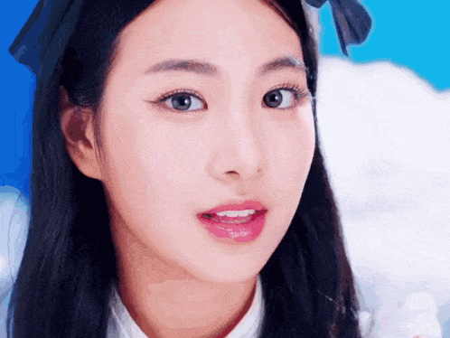 a close up of a young woman 's face with a blue background