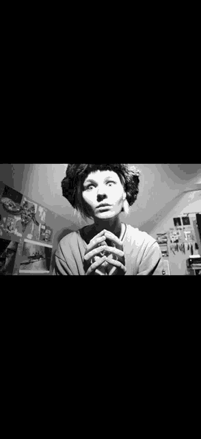 a black and white photo of a woman with her hands folded in front of her face