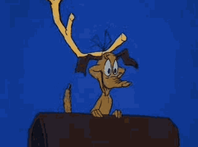 a cartoon dog with antlers is sticking its tongue out while standing on a log .
