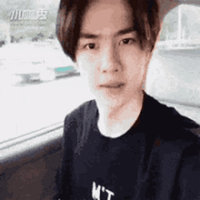 a young man is taking a selfie in a car while wearing a black t-shirt .