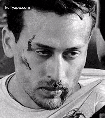 it is a black and white photo of a man with a beard and a scar on his face .