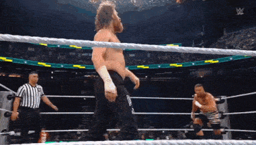 a man in a wrestling ring with a referee and a sign that says w