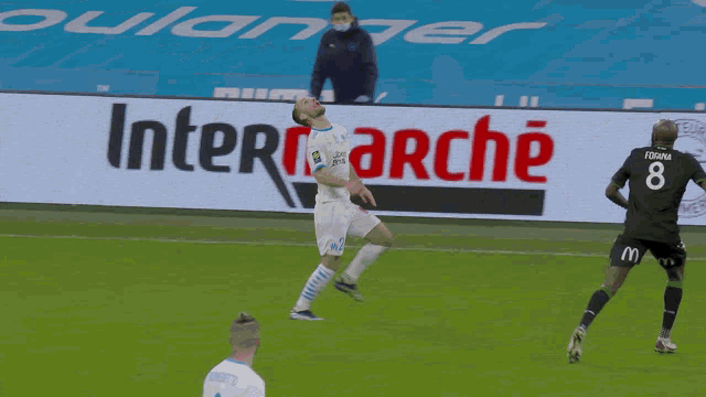 two soccer players on a field with an intermarché sign in the background