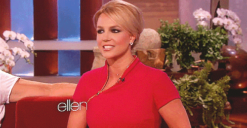 a woman in a red shirt is sitting in front of a sign that says ellen