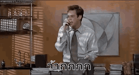 a man in a suit and tie is talking on a cell phone in a room .