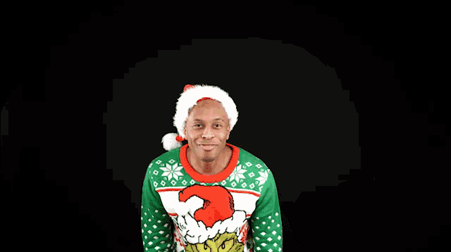 a man wearing a grinch christmas sweater and santa hat
