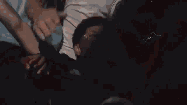 a group of people are holding a man 's head in a room .