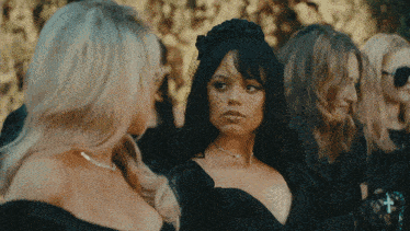 a woman with a veil on her head is surrounded by blonde women