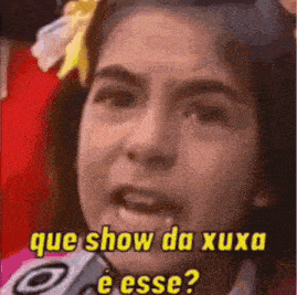 a woman is talking into a microphone with the words que show da xuxa e esse written above her .