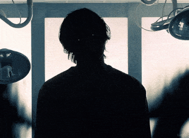 a silhouette of a person in a dark room with a light behind them