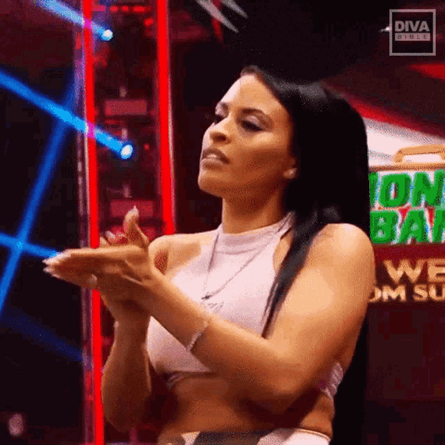 a female wrestler is clapping her hands in front of a sign that says diva