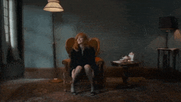 a woman with red hair is sitting in a chair