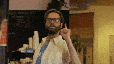 a man with glasses and a beard giving a thumbs up