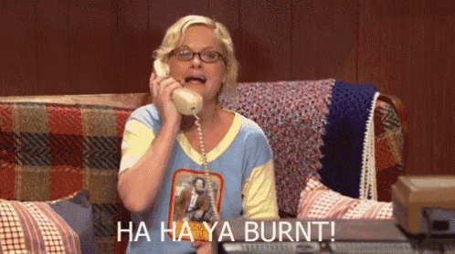 a woman is sitting on a couch talking on a telephone and says ha ha ya burnt