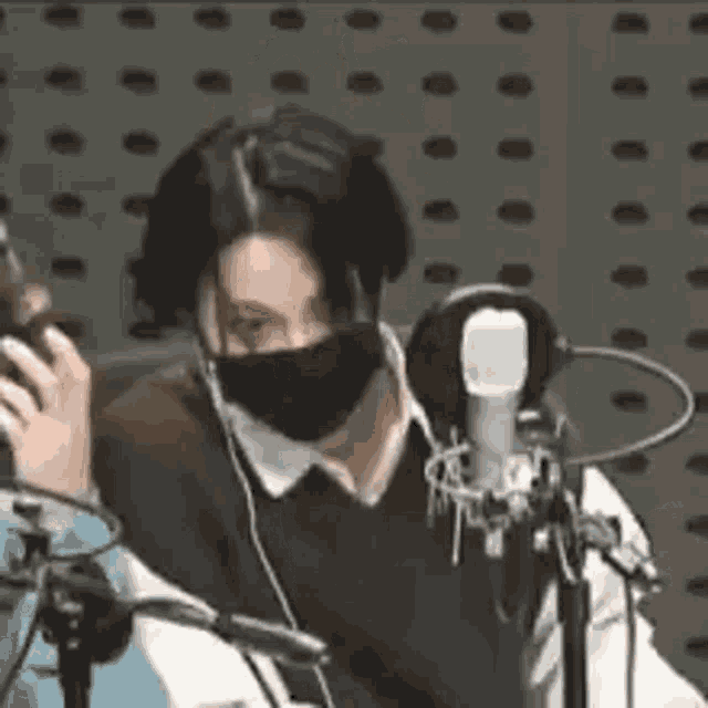 a woman wearing a mask is standing in front of a microphone in a studio .