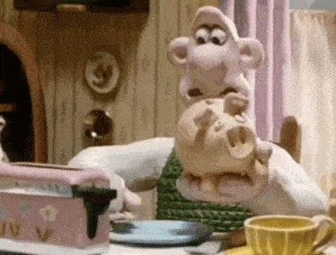 a cartoon character is sitting at a table with a pink toaster and a cup of coffee .
