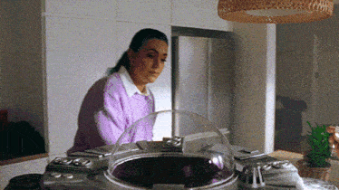 a woman in a purple sweater is sitting at a table with a purple object in front of her