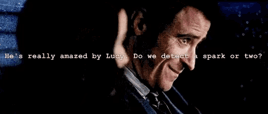 a man and a woman are looking at each other with the words he 's really amazed by lucy do we detect a spark