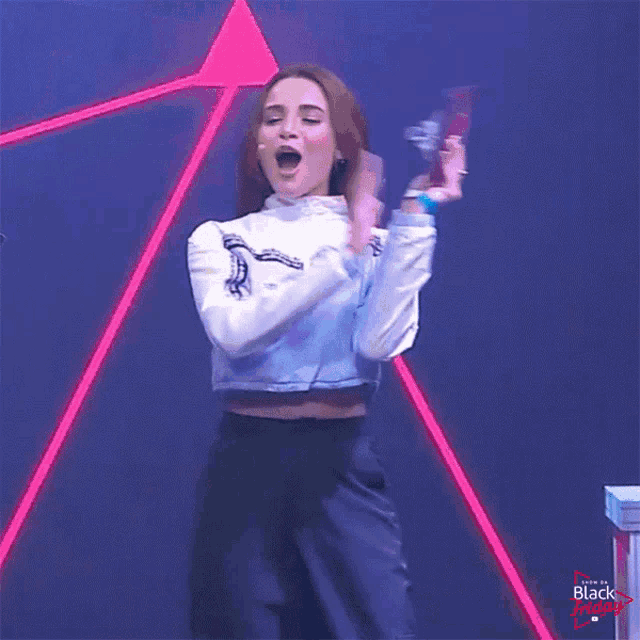 a woman in a white crop top and black pants is dancing on a stage with the words black friday in the corner