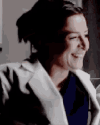 a close up of a woman wearing a white coat smiling