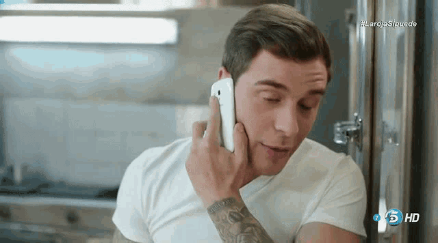 a man in a white shirt is talking on a cell phone in front of a 5 hd logo