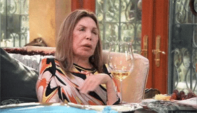 a woman is sitting on a couch with a glass of wine and a plate of food .