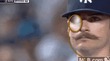a man wearing a ny yankees hat and glasses looks at the camera