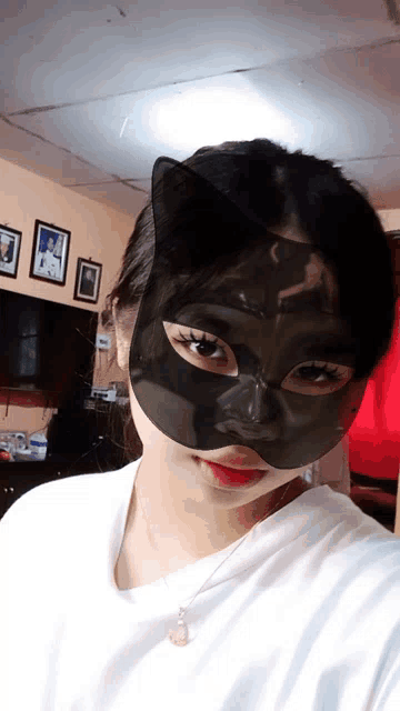 a woman wearing a black cat mask is taking a picture of herself