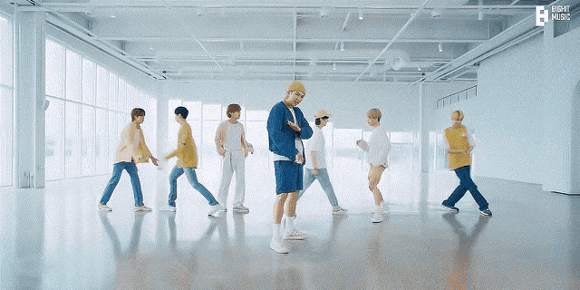 a group of young men are dancing in an empty room with eight music written above them