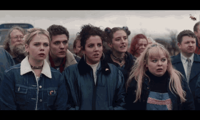 a group of people are standing in front of a blue bus that says ' o'neill ' on the side