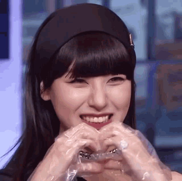 a young woman is making a heart shape with her hands .