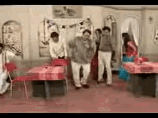 a group of people are standing in a room dancing .