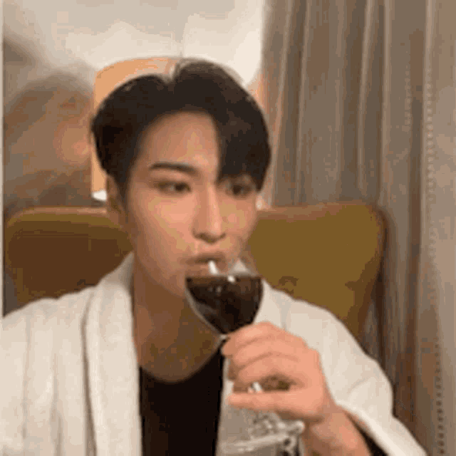 a man in a white robe is drinking a glass of wine .