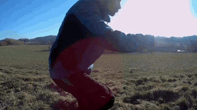 a man in a blue and black jacket is jumping in a field