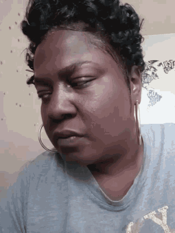a woman wearing hoop earrings and a grey shirt with the letter y on the front