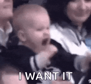 a baby is crying while being held by a woman in a crowd .