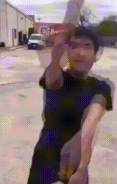 a man in a black shirt is standing on a street holding a piece of paper in his hand