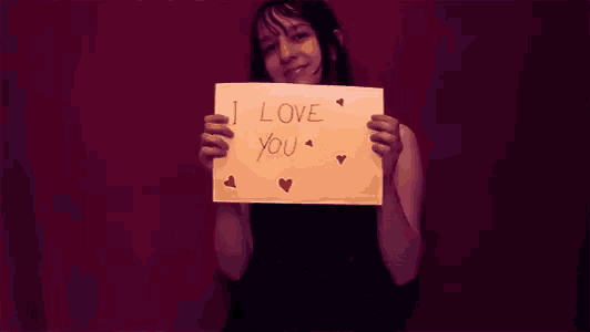 a woman is holding a piece of paper that says i love you